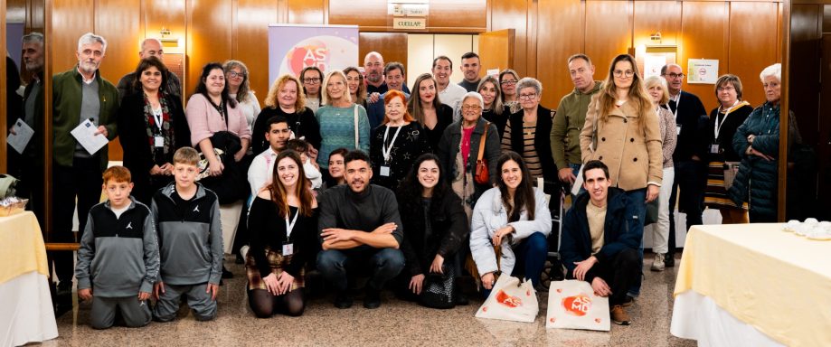Grupo de personas sonriendo y posando en un evento dentro de un salón.
