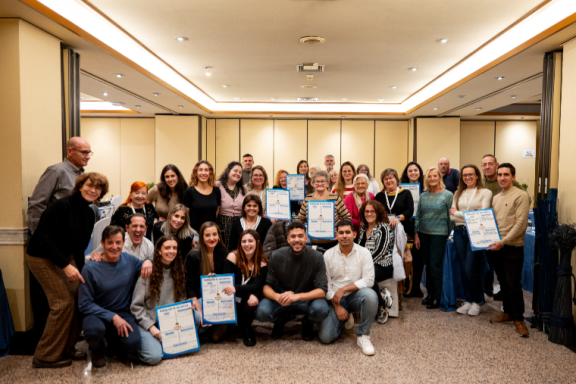 Grupo de personas sonriendo, sosteniendo diplomas en un evento social.